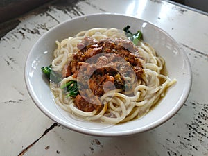 One bowl of chicken noodles (Mie Ayam) with sauteed chicken chunks, thick broth, and chewy noodles.