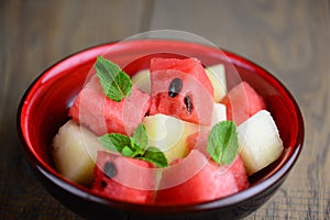 One bowl of mixed tropical fruit salad: watermelon and melon on a wooden table. Juicy vitamin salad of summer.