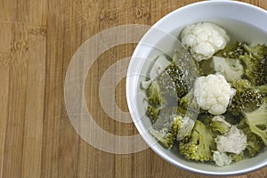 One bowl of soup with pieces of chicken, broccoli and cauliflower