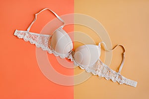 One bra of beige color on pastel orange and yellow background