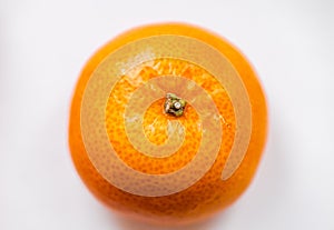 One bright ripe orange glossy tangerine in orange peel on white background. Top view. Close-up