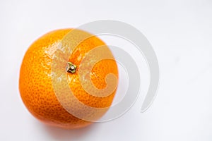 One bright ripe orange glossy tangerine in orange peel on white background. View from above. Top view