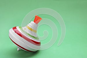 One bright spinning top on green background, space for text. Toy whirligig