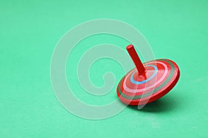 One bright spinning top on green background, space for text. Toy whirligig