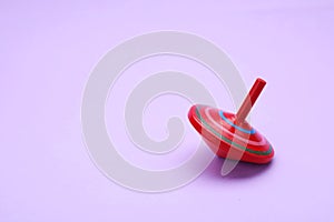 One bright spinning top on lilac background, space for text. Toy whirligig