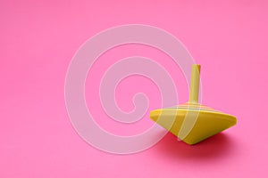 One bright spinning top on pink background, space for text. Toy whirligig