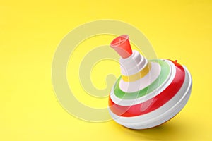 One bright spinning top on yellow background, closeup with space for text. Toy whirligig