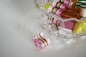 One broken piece of ribbon candy beside filled bowl.