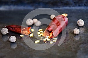 One broken pod of hot red pepper with seeds on on an old metal black tray, dried bitter chili pepper and fragrant pepper