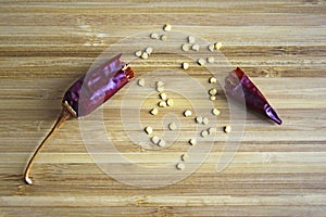 One broken pod of hot red pepper with seeds on wooden background, dried bitter chili pepper