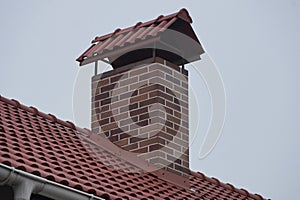 One brown brick chimney on red tiles on the roof