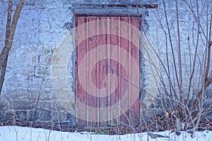 one brown closed wooden door on a gray brick wall of a private old house