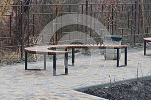 One brown wooden semicircular bench stands on a gray sidewalk