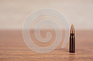 One bullet on a wooden background