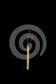 One burning match on a black background