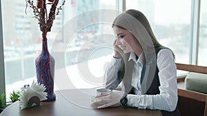 One business woman is sitting in a cafe and smiling and talking on the phone