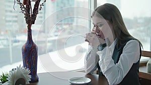 One business woman is sitting in a cafe and smiling and talking on the phone