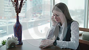 One business woman is sitting in a cafe and smiling and talking on the phone