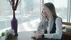 One business woman is sitting in a cafe and smiling and talking on the phone