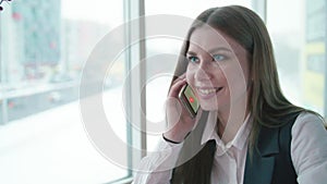 One business woman is sitting in a cafe and smiling and talking on the phone