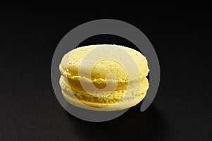 One cake of macaroni yellow lemon color. Delicious macaroon isolated on black background. French sweet cookie