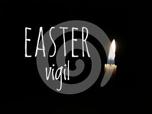One candle burn brightly on dark background with text written Easter vigil. photo