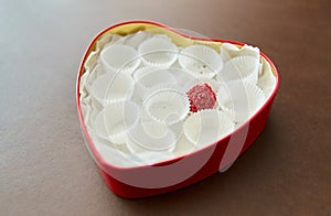 One candy in red heart shaped chocolate box