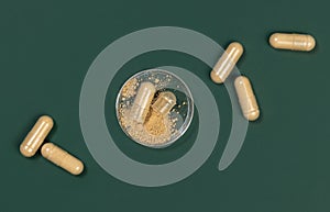 One capsule Opened in a jar on dark green. Taking dietary supplements with capsules