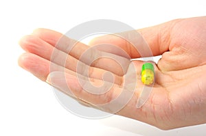 One capsule with yellow and green color in a beautiful woman hand