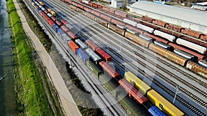 One cargo train passing by while others stand still, parked at the railway station