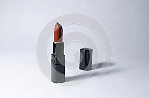One Carrot-colored Lipstick and black caps stand vertically at a distance from each other on a white background photo