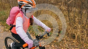 One caucasian children rides bike road in autumn park. Little girl riding black orange cycle in forest. Kid goes do