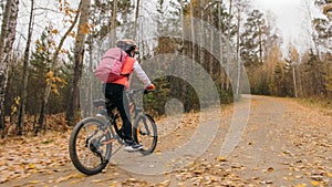 One caucasian children rides bike road in autumn park. Little girl riding black orange cycle in forest. Kid goes do