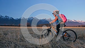 One caucasian children rides bike in wheat field. Little girl riding black orange cycle on background of beautiful snowy