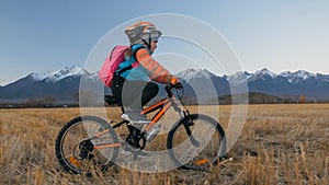 One caucasian children rides bike in wheat field. Little girl riding black orange cycle on background of beautiful snowy