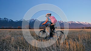 One caucasian children rides bike in wheat field. Little girl riding black orange cycle on background of beautiful snowy