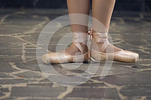 One Caucasian Female Ballet Dancer Legs In Laced Pointes Shoes While Posing With Straight Legs Outdoors On Tile Floor