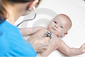 One caucasian female doctor is listening heartbeat of infant boy by stethoscope