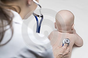 One caucasian female doctor is listening heartbeat of infant boy by stethoscope