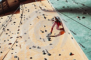 One Caucasian man professional rock climber workouts on climbing wall at training center in sunny day, outdoors. Concept