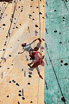 One Caucasian man professional rock climber workouts on climbing wall at training center in sunny day, outdoors. Concept