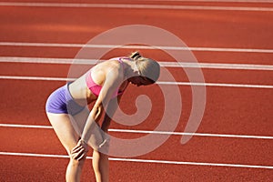 One Caucasian woman, female athlete, runner training at public stadium, sport court or palyground outdoors. Summer sport