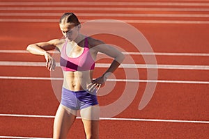 One Caucasian woman, female athlete, runner training at public stadium, sport court or palyground outdoors. Summer sport