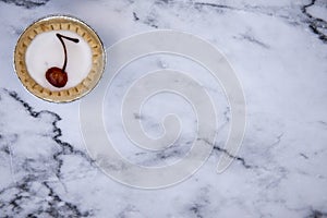One cherry bakewell tart on a marble background