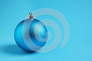 One Christmas ball on light blue background. Space for text