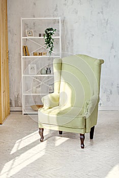 One classic olive armchair against a white wall and floor. Copy space. White sack. Scandinavian style