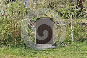 One closed brown metal door on a gray iron mesh fence