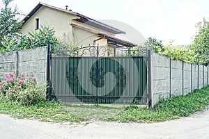 One closed green metal gate with a black wrought iron pattern