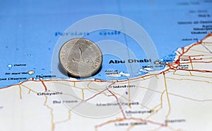 One coin of United Arab Emirates one dirham money on obverse put on the map near Abu Dhabi city. Concept of finance.
