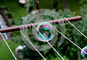 A one colourful bubble in the center of picture between cords for wet clothes. A bubble contain green and purple colour. In the bu